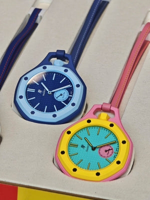 A close-up of a dark blue and a vibrant yellow Audemars Piguet x Swatch Royal Pop watches arranged neatly in the presentation packaging.